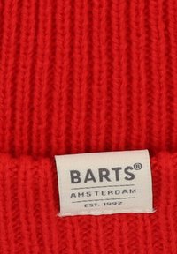 Red knitted beanie with ribbed texture and a white fabric label displaying "BARTS AMSTERDAM EST. 1992."