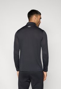 Μαύρο μακρυμάνικο τοπ με ψηλό γιακά, κατασκευασμένο από ελαφρύ ύφασμα. Διαθέτει μικρό λογότυπο στο πίσω μέρος και εφαρμοστή σχεδίαση με απαλό υφή.