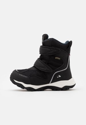 Sort højt vinterstøvle med velcrobånd, hvid sål, vandtæt Gore-Tex mærkat og robust profil til udendørs brug.