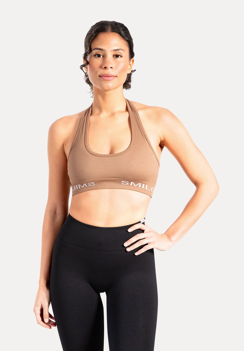 Bruin geribd sportbeha met brede bandjes, een ronde halslijn en de tekst "SMILOVE" langs de zoom, gecombineerd met zwarte leggings met hoge taille.