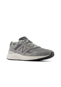 Gray athletic shoe with a mesh and suede upper, featuring a prominent white "N" logo, grey laces, and textured midsole for cushioning.