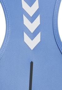 Ljusblå atletisk topp tillverkad av strukturerad tyg med vita chevronmönster och ett svart vertikalt sträck i mitten.