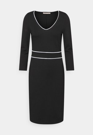 Sort kjole til knæet med lange ærmer, V-hals og hvide kantdetaljer ved halsudskæring og talje.