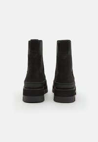 Stivaletti neri con tomaia in suede, dettagli in pelle liscia e suole in gomma spessa e testurizzata con un leggero tacco.