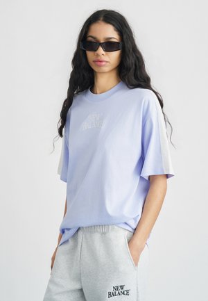 Világoslila, pamutból készült rövid ujjú, kerek nyakú póló, amelynek a mellkasán hímzett "New Balance" logó található.