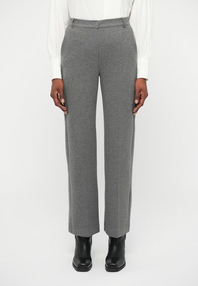 Pantalons en matière laine grise avec une coupe droite, bouton sur la ceinture et poches avant, associés à des bottines noires à la cheville.
