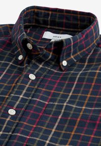 Camicia a quadri di cotone con motivi a scacchi in blu navy scuro, rosso, verde e arancione, con collo abbottonato e bottoni bianchi visibili. Etichetta con la scritta "NEXT".