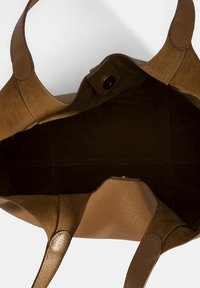 Bruine leren tote bag met suede accenten, met een ruime binnenkant, dubbele handgrepen en een drukknoopsluiting. Getextureerde buitenkant met een zachte afwerking.
