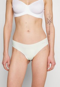 Sous-vêtements vert clair avec une texture lisse et un design minimaliste. Présente une large ceinture et une finition sans coutures.