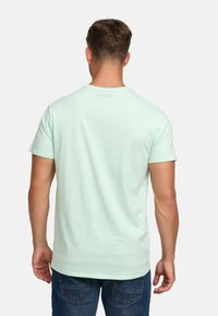 Light mint green cotton t-shirt with a crew neckline, short sleeves, and a relaxed fit, worn with blue denim jeans.
