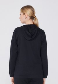 Sweat-shirt à capuche noir en tissu doux. Doté de manches longues, d'une coupe décontractée et d'une poche kangourou. Design sobre, sans motifs visibles.