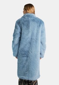 Cappotto in pelliccia sintetica di colore azzurro chiaro con una texture morbida e soffice. Presenta un ampio colletto e maniche lunghe, arrivando a metà coscia sul retro.