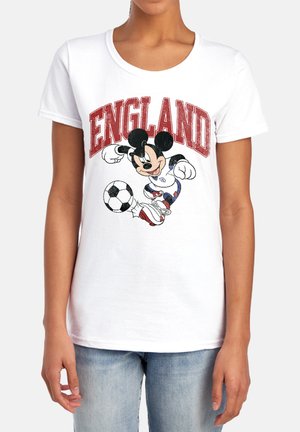 Person trägt ein weißes T-Shirt mit dem Schriftzug „ENGLAND“ und einer Grafik von Mickey Mouse, der einen Fußball kickt, vorne drauf.