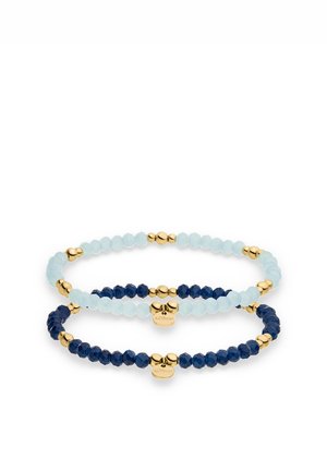 Two beaded stretch bracelets with faceted light blue and dark blue beads, gold accents, and small gold brand tags.
