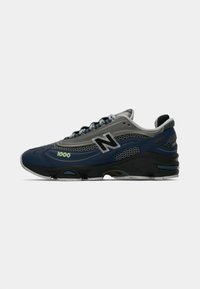 Tamno plava i siva New Balance 1000 tenisica s mrežastim detaljima, crnim srednjim dijelom i bijelim potplatom, prikazana u profilu s desne strane.