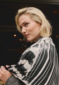 Schwarz-weißer, gemusterter Schal, der über die Schultern gelegt ist, mit diagonalen Streifen und weichem, glattem Stoff mit leichtem Schimmer.