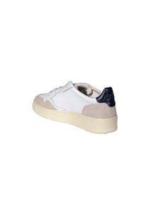 Sneaker bianca in pelle con accenti in suede beige, una linguetta sul tallone di colore blu navy e una suola in gomma texturizzata. Presenta lacci piatti e perforazioni per la traspirabilità.