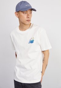 New Balance ATHLETICS RELAXED GOLF CARTOON - Apdrukāts T-krekls - sea salt