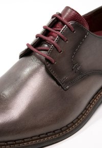 Scarpa da dress in pelle marrone con finitura lucida, lacci bordeaux e dettagli di cucitura sottili lungo i lati e il tallone.