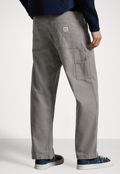 Harmaat cargohousut, joissa on useita taskuja ja rento malli, valmistettu kestävästä kankaasta. Yhdistetty sinisiin kangastennareihin.