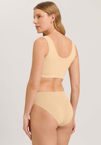 Conjunto de bralette sin costuras y ropa interior de cintura alta en color beige. Presenta una tela suave y elástica con un diseño minimalista sin adornos.