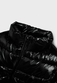 Giubbotto piumino nero con colletto alto, texture lucida e chiusura a zip. Presenta segmenti trapuntati orizzontali per l'isolamento.