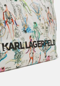 Drobė maišelis su spalvingais mados eskizais ant balto fono, apačioje juodu šriftu užrašyta "KARL LAGERFELD".