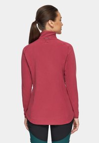 Polarowy sweter w kolorze burgundowym z wysokim kołnierzem i dopasowanym krojem. Posiada długie rękawy oraz subtelny detal z logo na plecach.