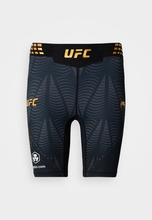 Juodi suspaudžiantys šortai su auksinėmis detalėmis, ant kurių yra UFC logotipas, bangų rašto tekstūra ir sustiprintas siuvimas palei kraštus.