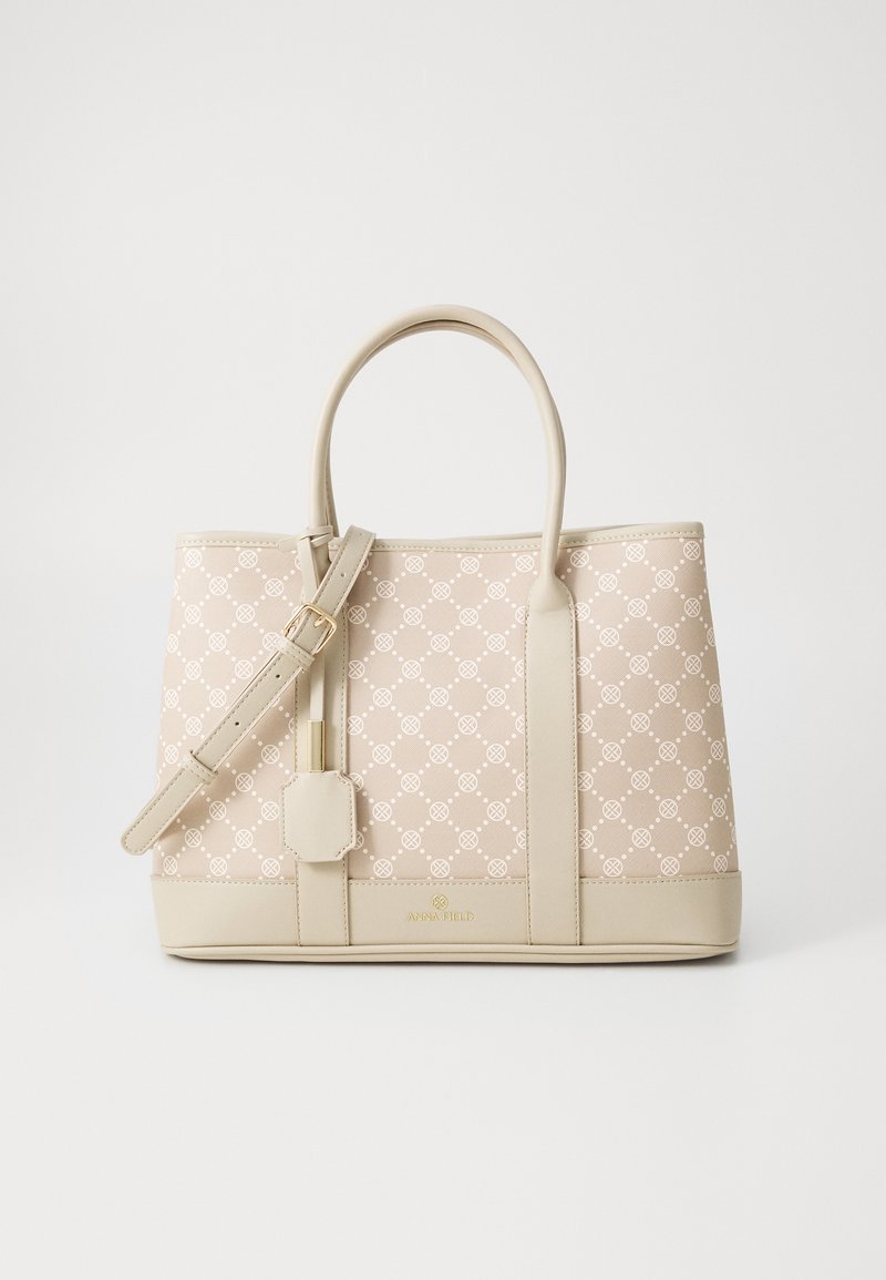 Sac à main beige de créateur avec corps à motifs, deux poignées, bandoulière réglable et boucle dorée sur un fond uni.