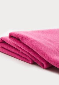 Folding textile in vibrant pink, made of soft wool. Features a smooth texture and clean edges, showcasing a cozy, warm appearance.
