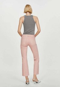 Top sin mangas gris combinado con unos vaqueros recortados de talle alto y color rosa. Los vaqueros tienen un dobladillo deshilachado y detalles en el bolsillo trasero.