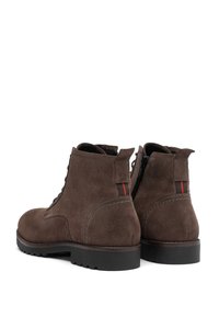 Ruske nubuk ankle softs dengan permukaan bertekstur, dilengkapi dengan resleting samping, tali depan, dan outsole karet hitam dengan traksi.