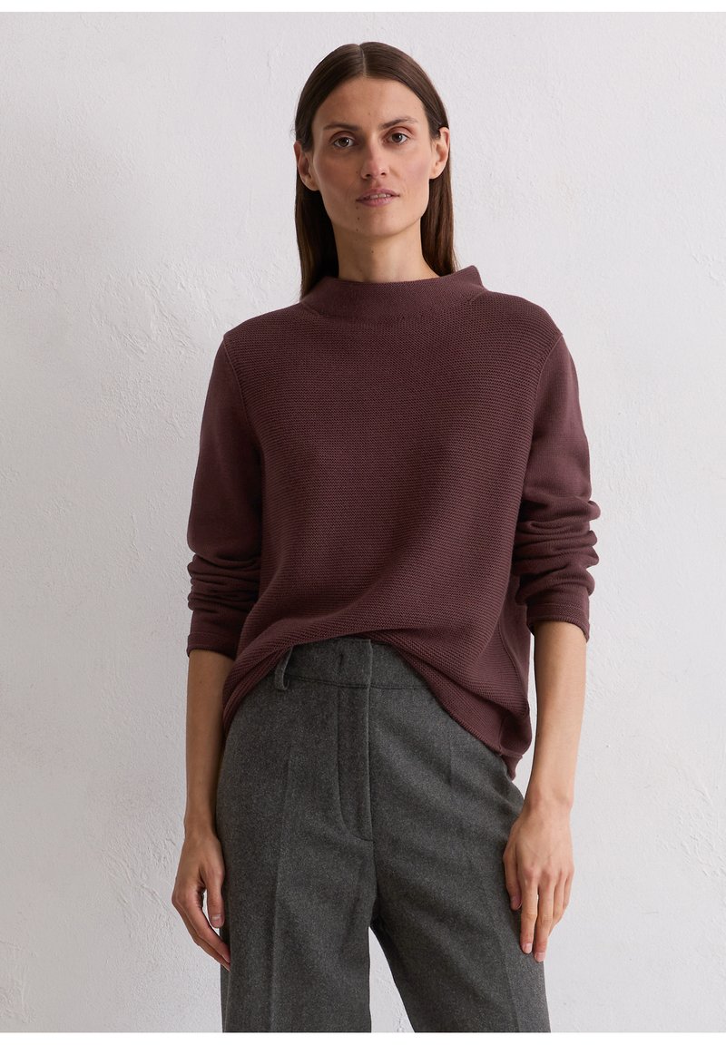 Maroon gebreide trui met een hoge hals en lange mouwen, gecombineerd met grijze op maat gemaakte broek. Zachte textuur en een casual pasvorm zijn zichtbaar.