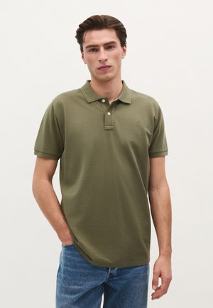 Polo verde măsliniu din material moale, cu guler și deschidere cu trei butoane, asortat cu blugi blue denim. Design simplu, cu mâneci scurte.