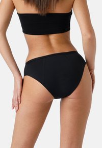 Mutande bikini nere con taglio alto e design senza cuciture, realizzate in un tessuto morbido e con una texture liscia, adatte per costumi da bagno.