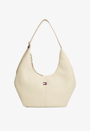 Kremowa teksturowana skórzana torba na ramię z pojedynczym paskiem i małym prostokątnym logo Tommy Hilfiger na przedzie, pośrodku.