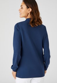 Marineblauw overhemd met lange mouwen, met een ontspannen pasvorm, kraag en een soepele textuur. Kenmerkt zich door subtiele stiksels en een middellange snit.