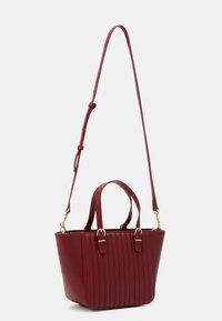 Burgunderfarbene synthetische Handtasche mit vertikaler Rippstruktur, goldfarbenen Beschlägen, doppelt kurzen Griffen und einem verstellbaren Schultergurt.