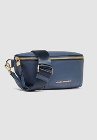 Borsa in pelle blu navy con zip dorata, forma rettangolare, tracolla regolabile e logo impresso. Texture liscia con dettagli lucidi.