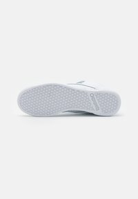 Białe sneakersy z fakturowaną podeszwą w kształcie plastra miodu, gładkim materiałem cholewki, minimalistycznym designem i subtelnymi akcentami logo.