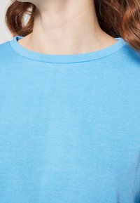 Light blue cotton t-shirt with a round neckline and short sleeves. The fabric appears smooth with a fine knit texture.