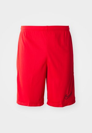 Red athletic shorts made of lightweight fabric, featuring a black logo accent, elastic waistband, and side vents for improved airflow.