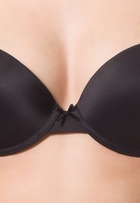 Black push-up bra featuring smooth fabric, a sleek design, and a decorative bow at the center, ideal for enhancing silhouette.