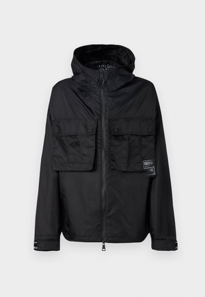 Zwarte zip-up jas met een capuchon, met twee voorzakken op de borst, een label op de linker zak en een gladde, glanzende textuur.