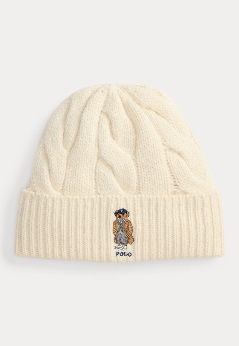 Kremowa dzianinowa czapka typu beanie z wzorem warkocza i prążkowanym mankietem, z haftowanym misiem w brązowym płaszczu i niebieskiej czapce nad napisem "POLO".