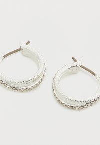 Σκουλαρίκια κρίκοι από ασήμι με σχεδίαση στριμμένου σχοινιού και σειρά από καθαρά πολύτιμα λίθια κατά μήκος της κάτω ακμής. Απλή κούμπωμα με καρφί.