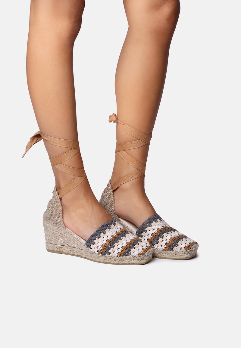 Vedge espadrilas ar patsietu jūtu zoli, ar tamborētu augšu baltā, pelēkā un brūnā svītrā, un krustveida potīšu auklu.