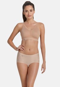Nude komplecik braletki i majteczek typu boyshort wykonany z gładkiego materiału, z lekkim wypełnieniem, regulowanymi ramiączkami i siateczkowymi akcentami po bokach.