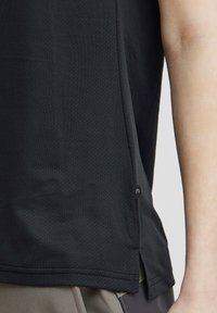 Must kasukate tahtmine, millel on tekstuurne kangas, külgsuunised ja väike logo silt. Kujundus rõhutab hingavust ja liikumise mugavust.